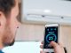 Young man using smart application to adjust temperature of air conditioning after servicing